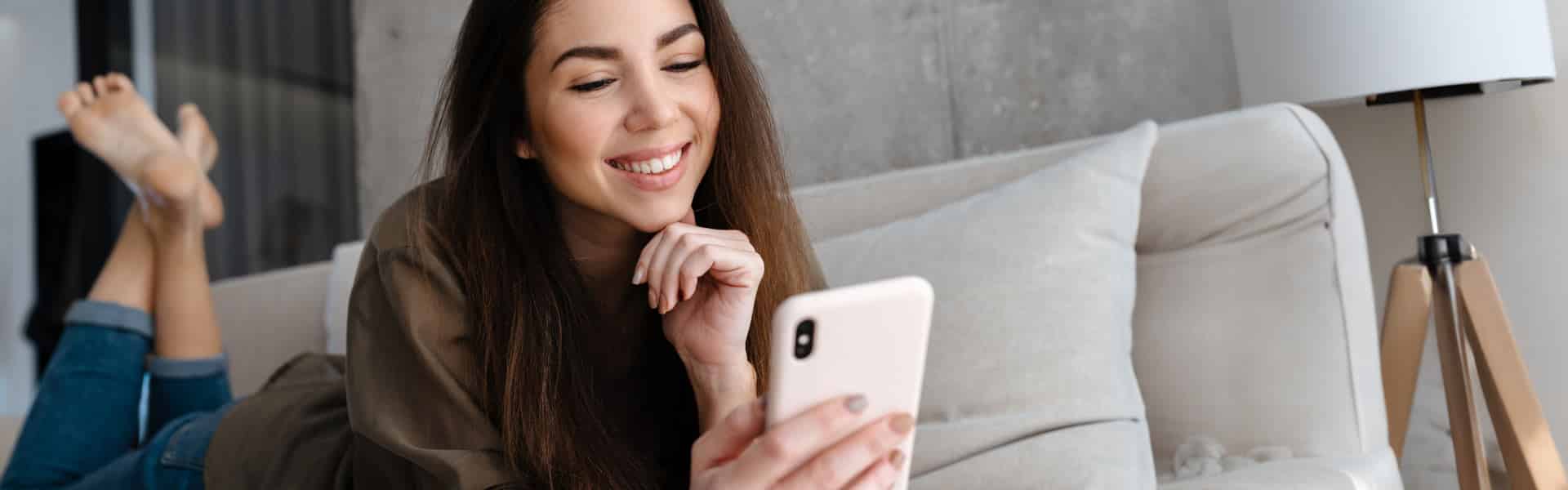 Frau auf dem Sofa die in Google am Smartphone etwas sucht